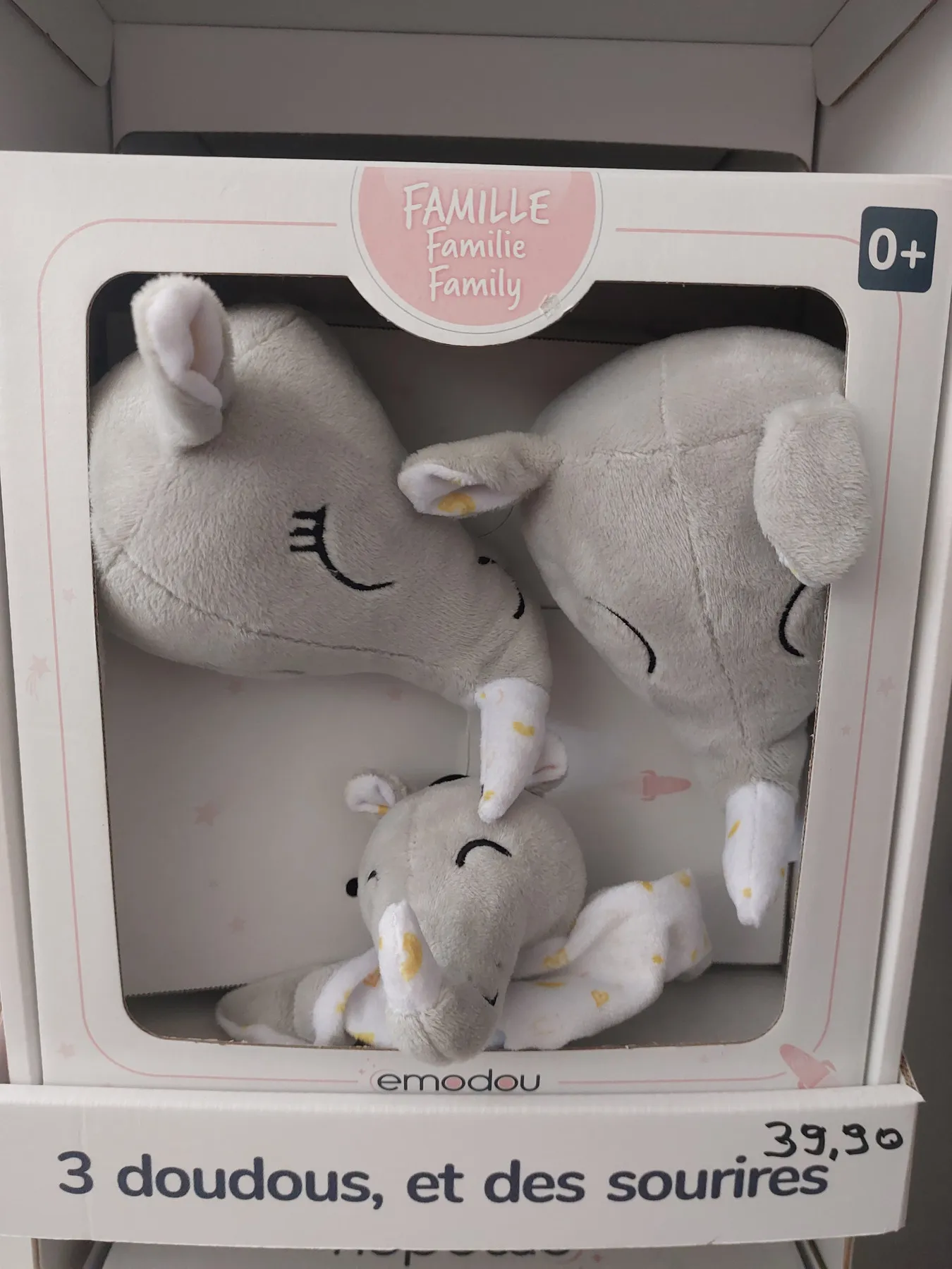 Un coffret de trois doudous gris en peluche, encore dans son emballage.