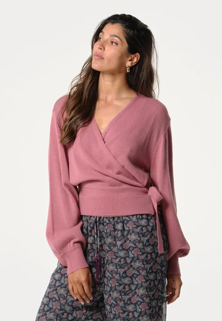Une femme porte un gilet cache-coeur rose de la marque Cecil.